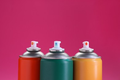 Photo of Many spray paint cans on pink background, closeup. Space for text