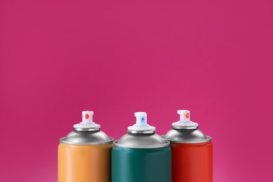 Many spray paint cans on pink background, closeup. Space for text