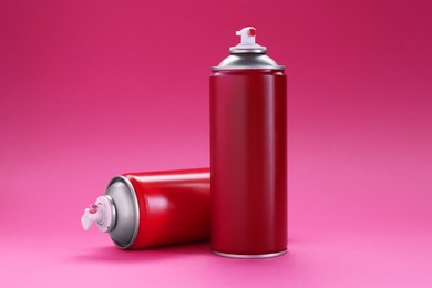 Photo of Two spray paint cans on pink background