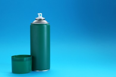 Green spray paint can on light blue background, space for text