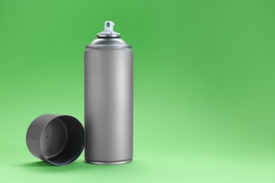 Photo of Gray spray paint can on green background, space for text