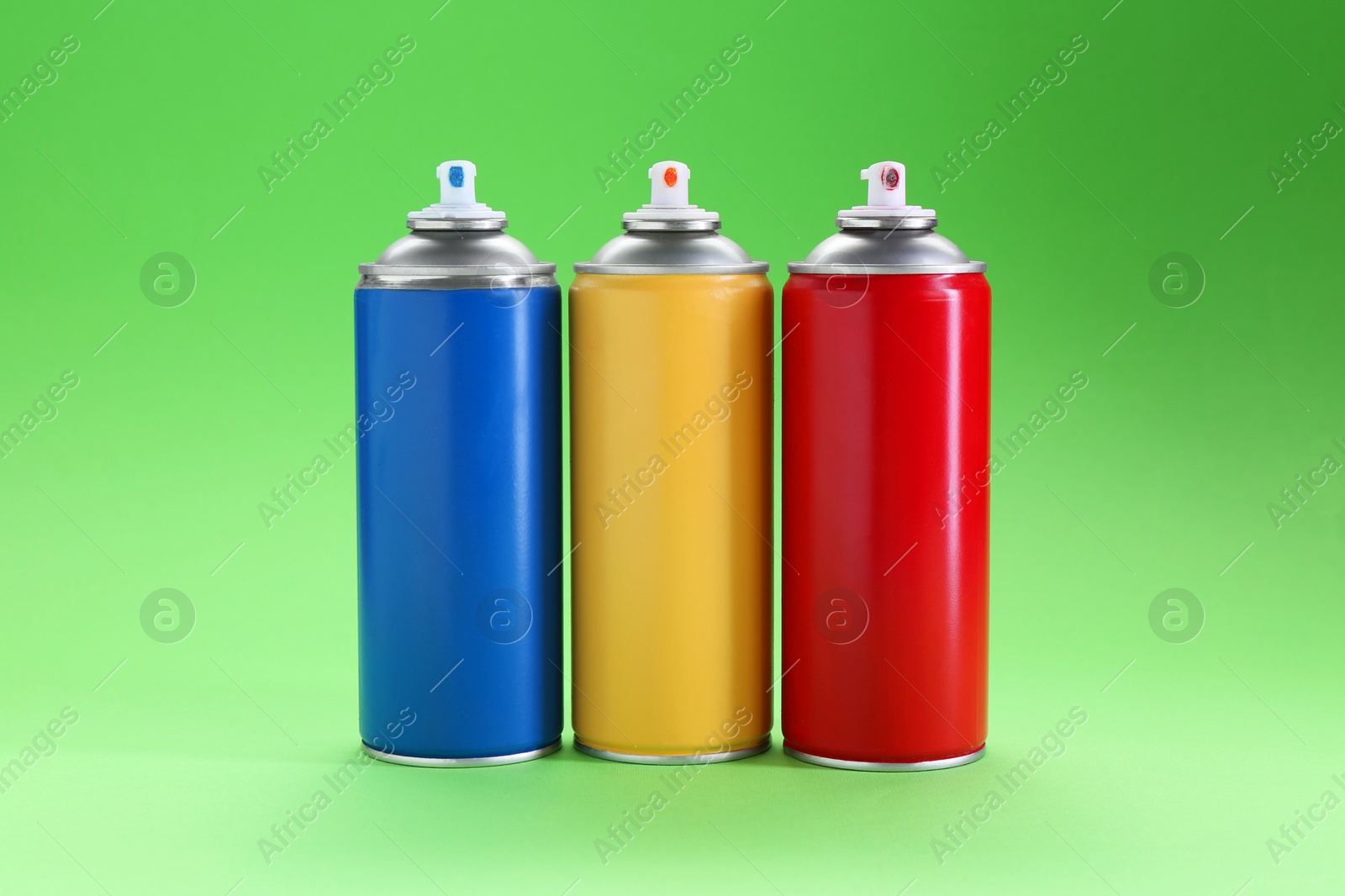 Photo of Many spray paint cans on green background