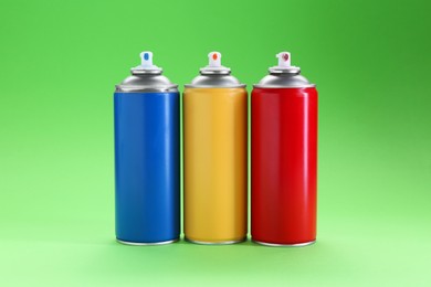 Many spray paint cans on green background