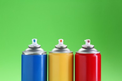 Photo of Many spray paint cans on green background, closeup. Space for text