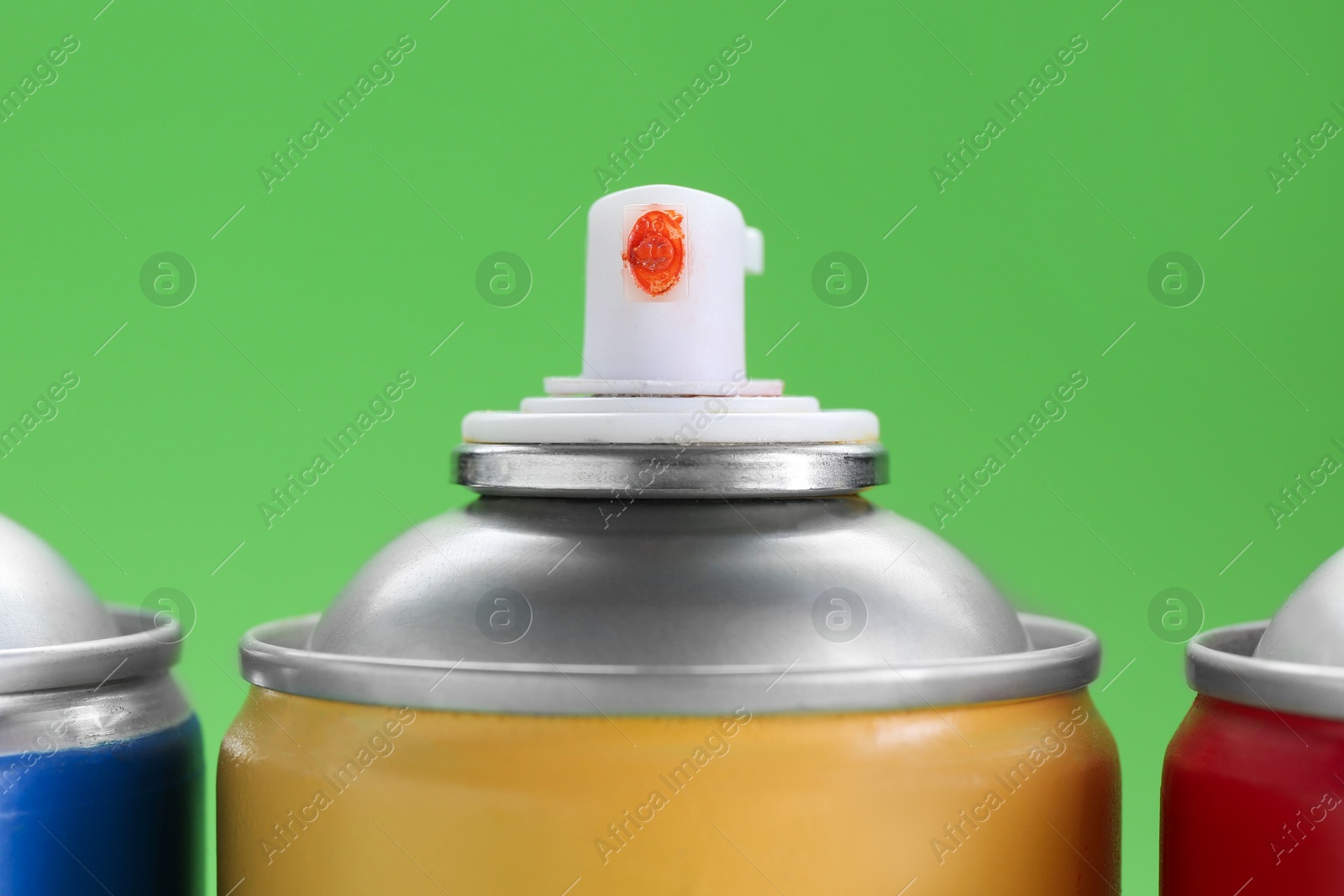 Photo of Many spray paint cans on green background, closeup