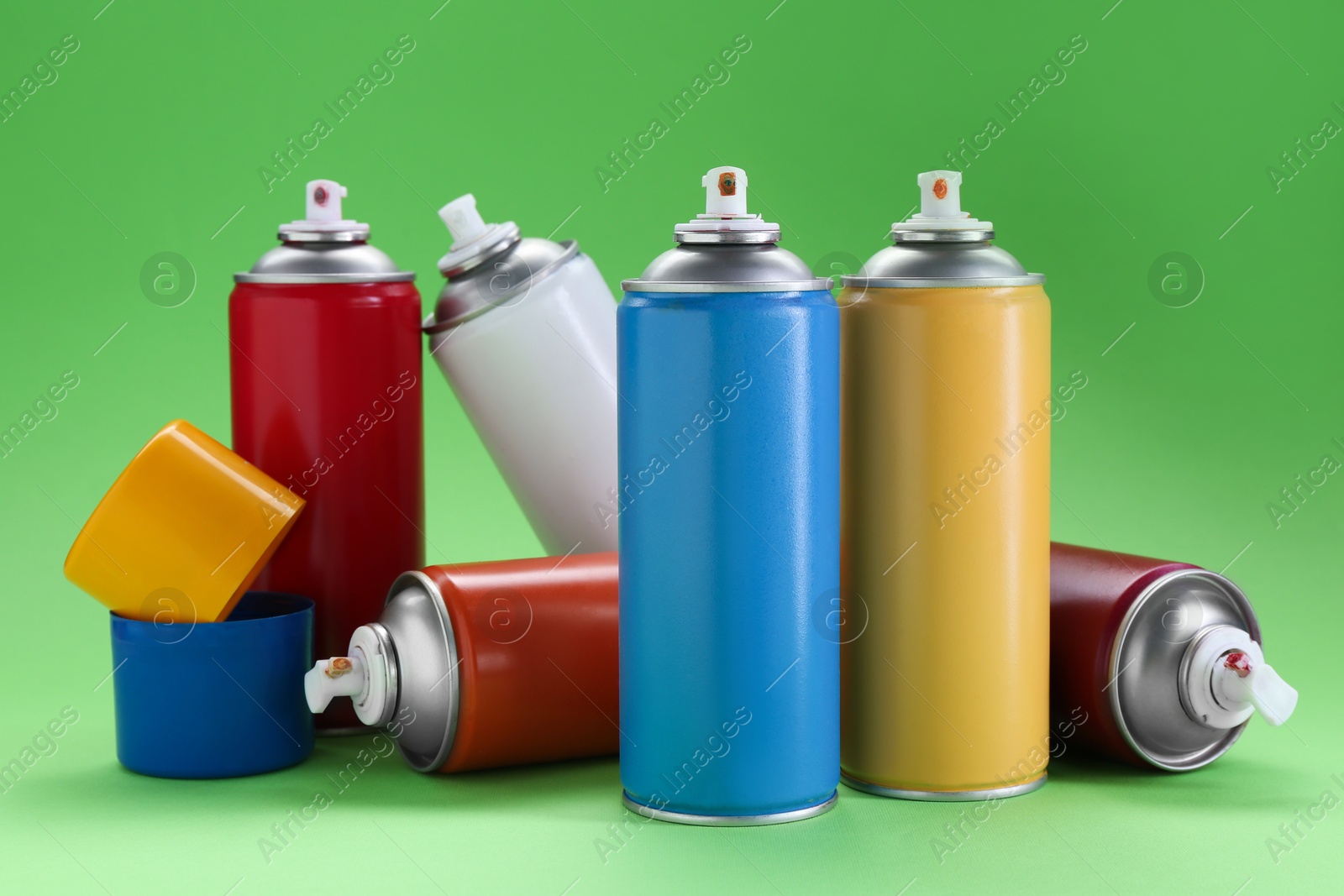 Photo of Many spray paint cans on green background