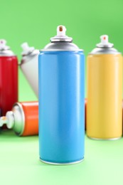 Photo of Many spray paint cans on green background, closeup