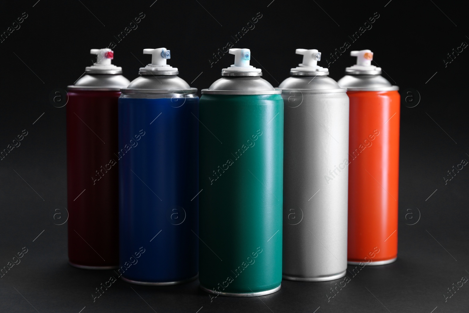 Photo of Many spray paint cans on dark gray background