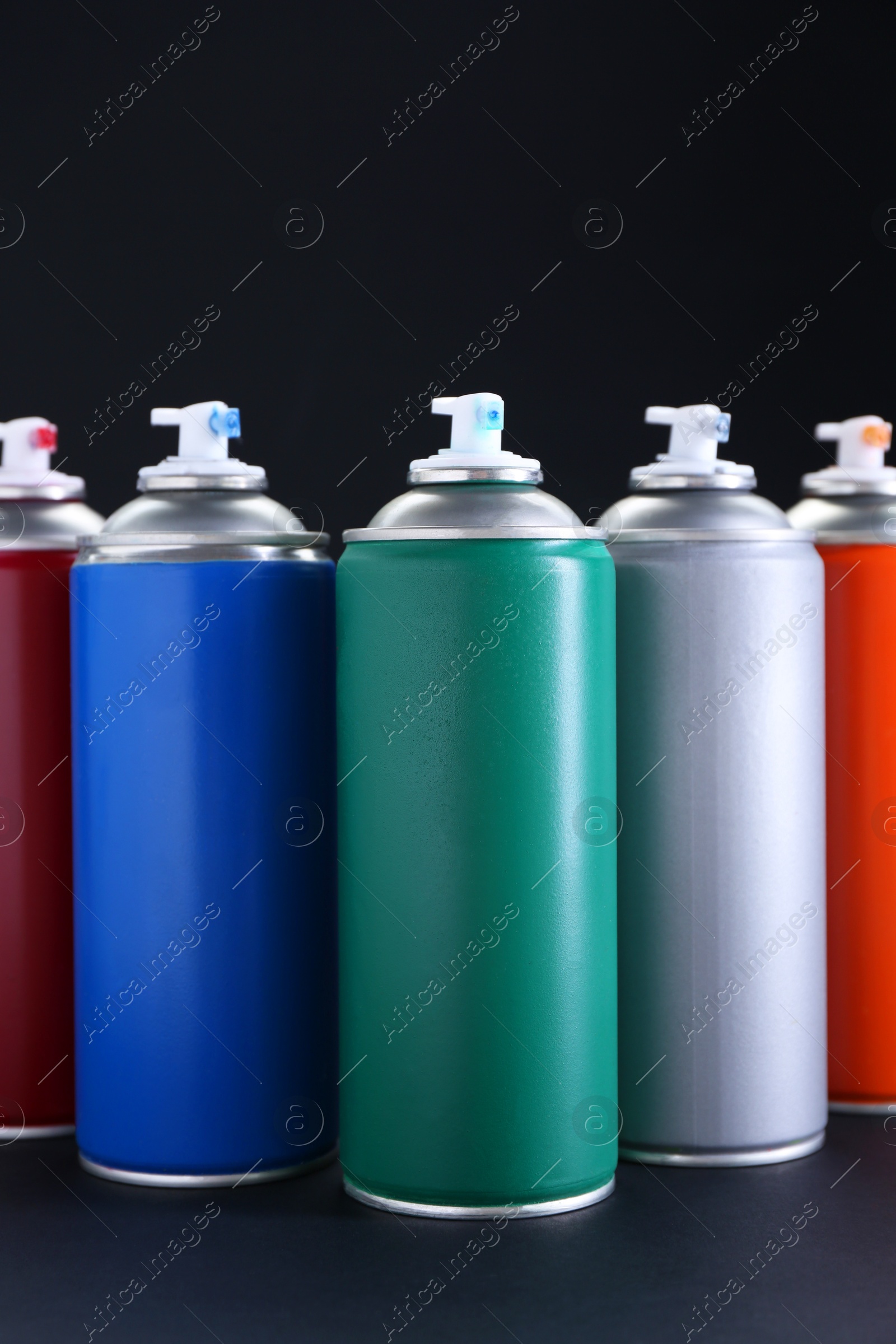 Photo of Many spray paint cans on dark gray background