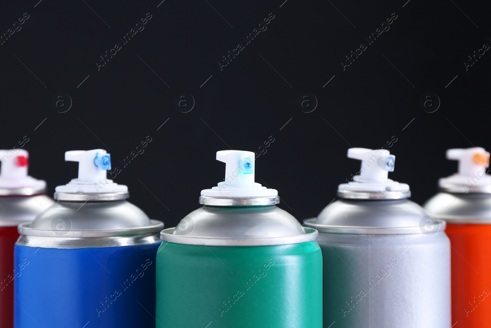 Photo of Many spray paint cans on dark gray background, closeup. Space for text