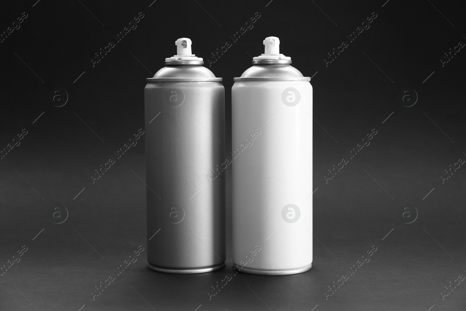 Photo of Two spray paint cans on dark gray background