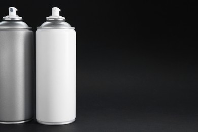 Photo of Two spray paint cans on dark gray background, space for text