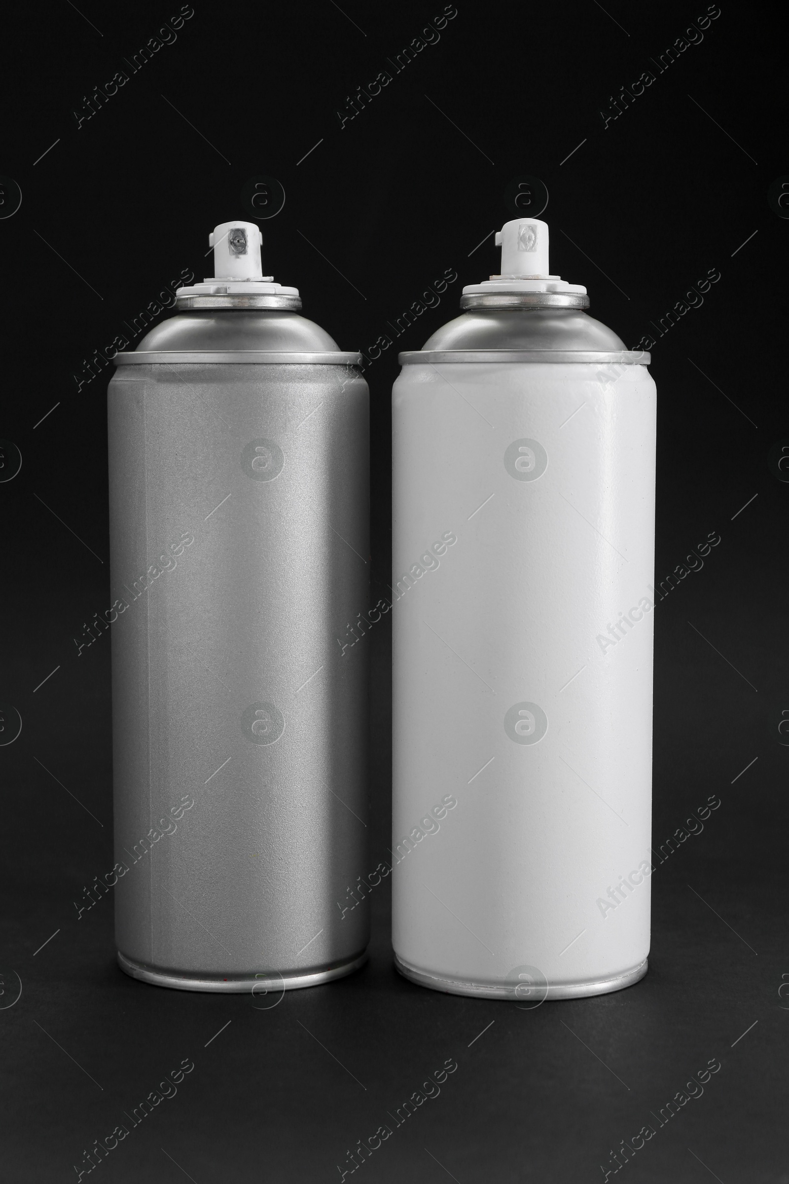 Photo of Two spray paint cans on dark gray background