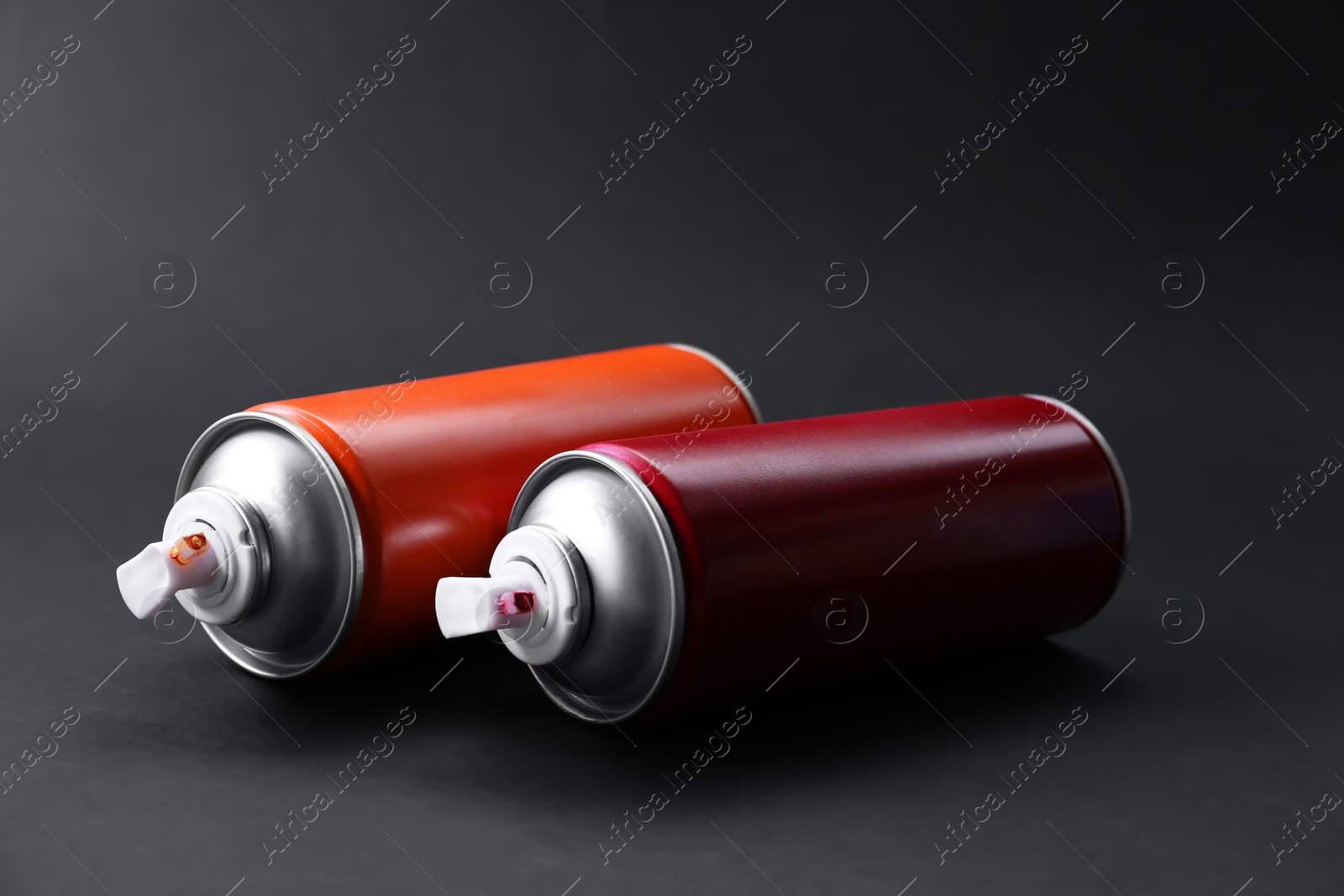 Photo of Two spray paint cans on dark gray background