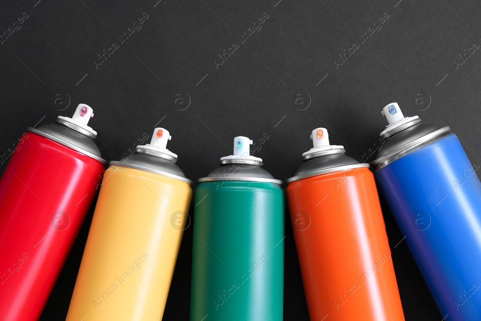 Photo of Many spray paint cans on dark gray background, top view. Space for text