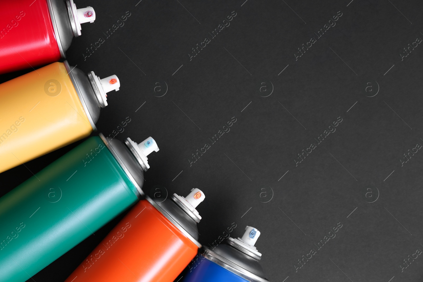 Photo of Many spray paint cans on dark gray background, top view. Space for text