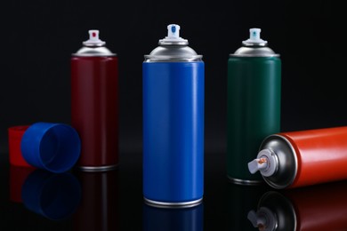 Photo of Many spray paint cans on black background