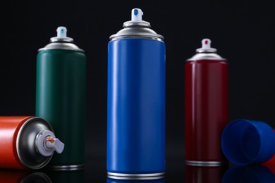 Photo of Many spray paint cans on black background, closeup