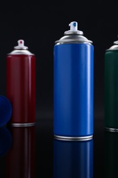 Photo of Many spray paint cans on black background