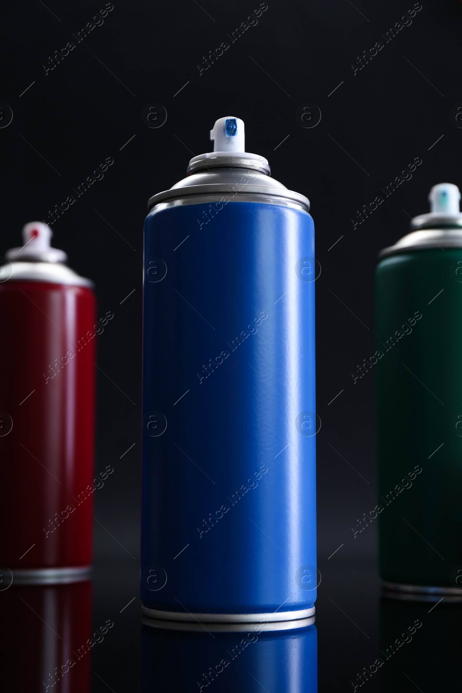 Photo of Many spray paint cans on black background