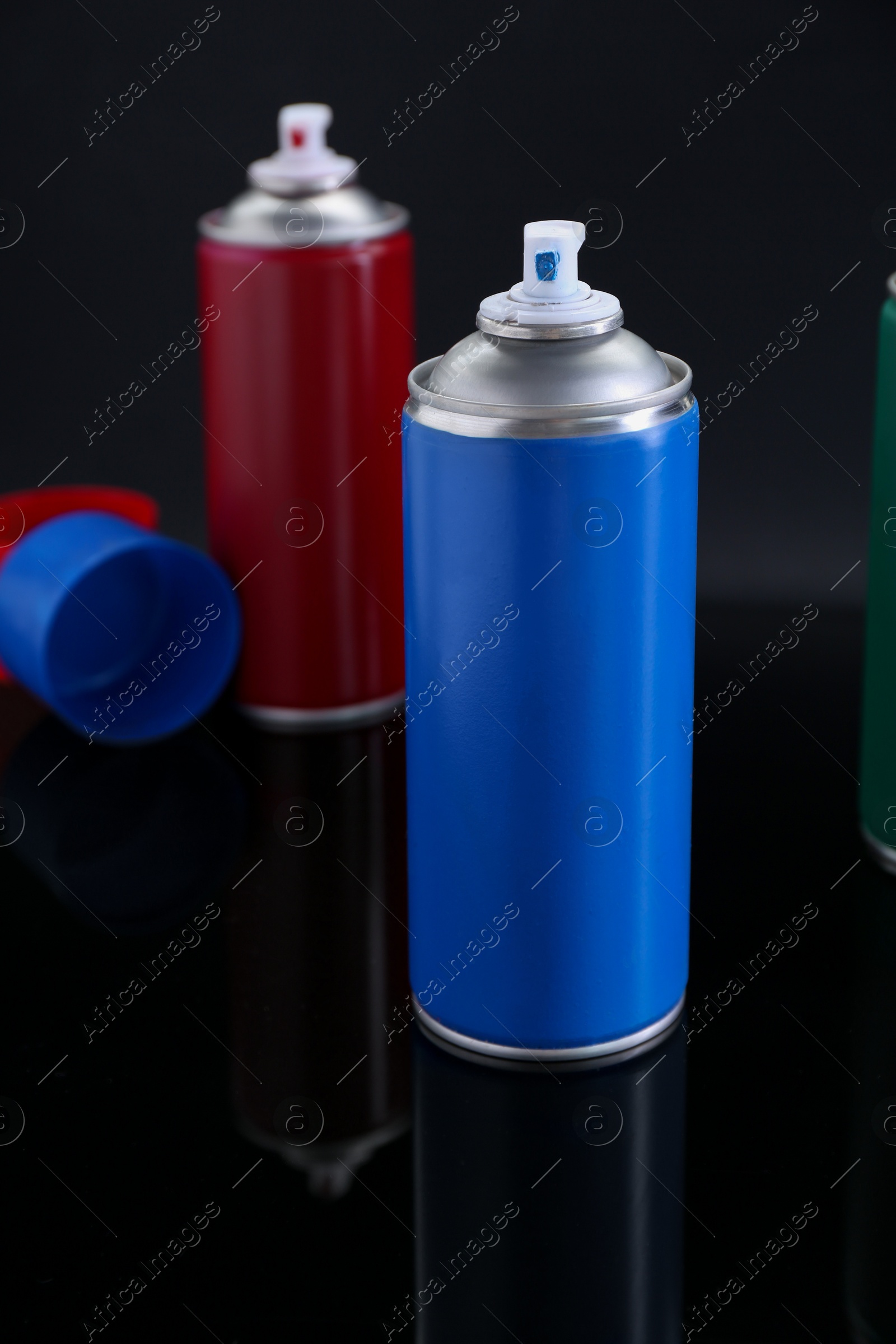 Photo of Two spray paint cans on black background