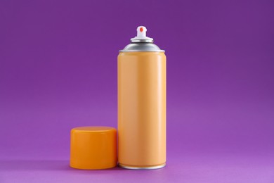 Photo of Orange spray paint can on violet background