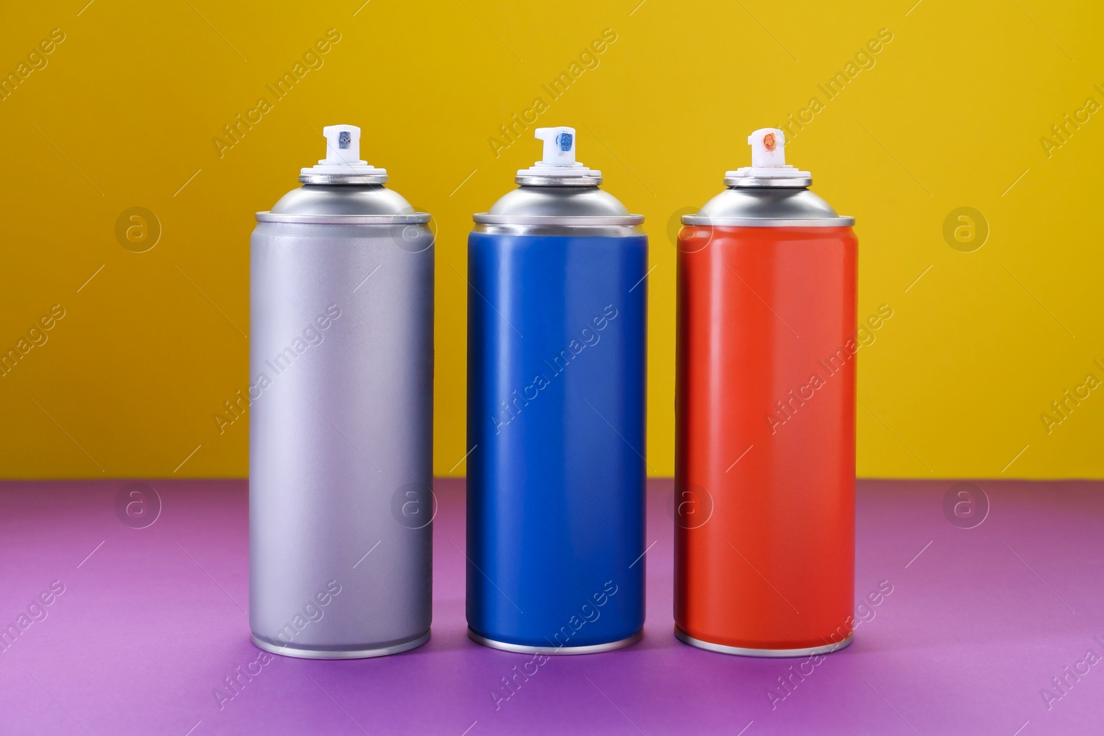 Photo of Many spray paint cans on color background