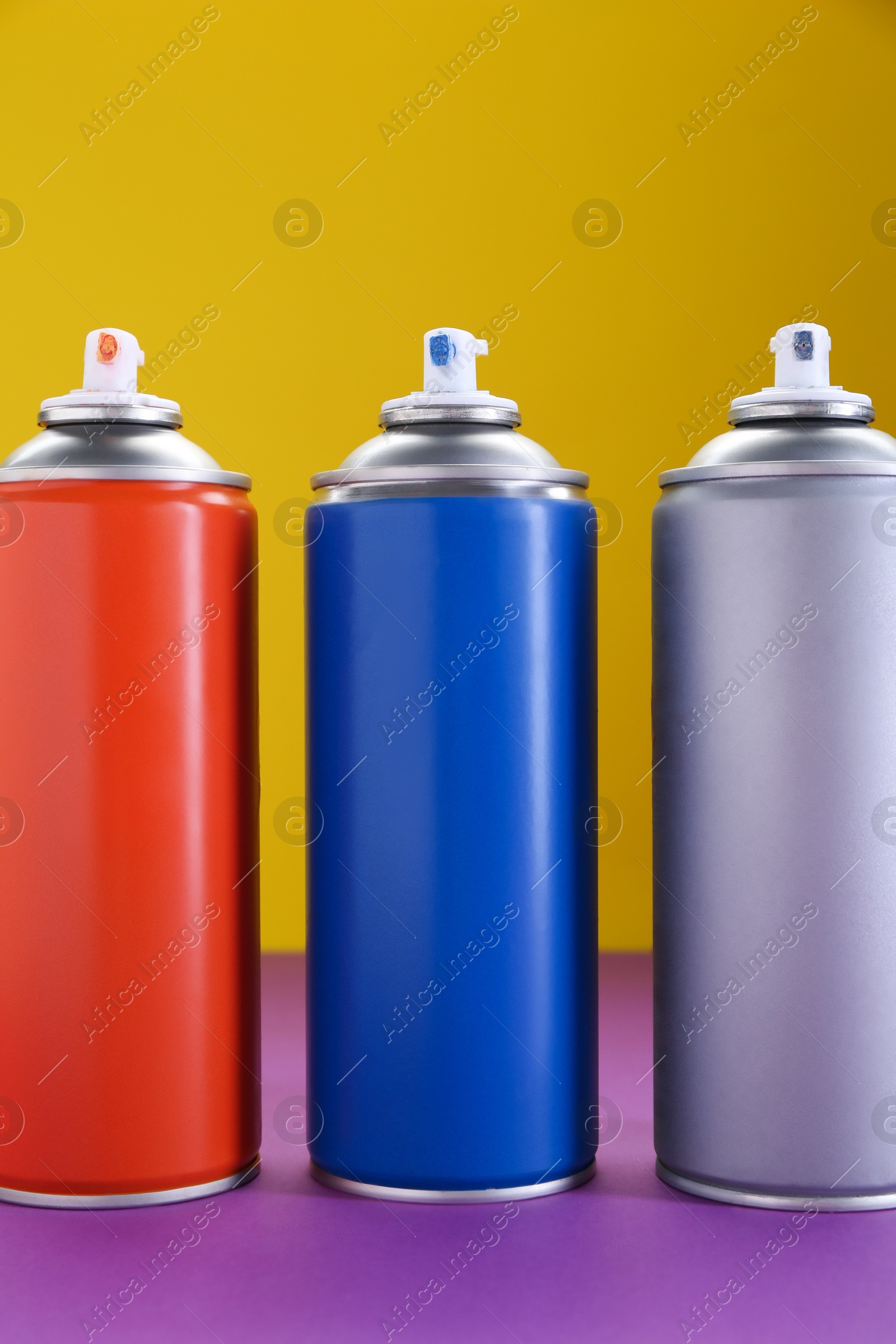 Photo of Many spray paint cans on color background