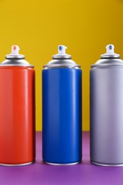 Many spray paint cans on color background