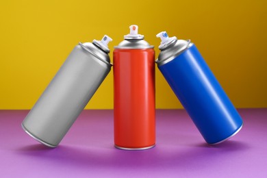 Many spray paint cans on color background