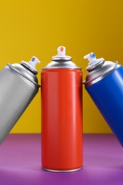 Many spray paint cans on color background