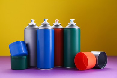 Photo of Many spray paint cans on color background