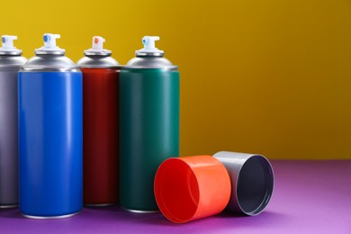 Many spray paint cans on color background, space for text