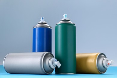 Many spray paint cans on color background