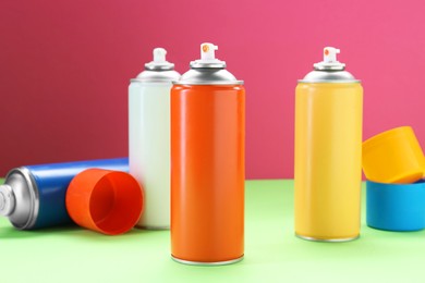 Many spray paint cans on color background