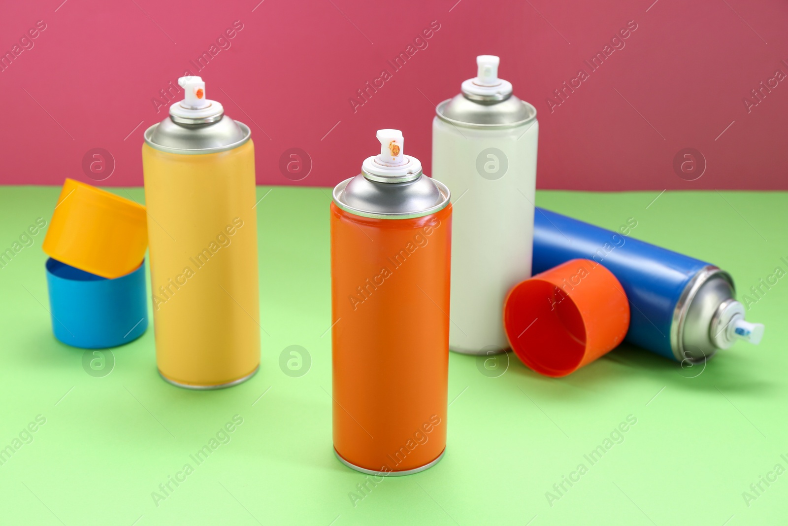 Photo of Many spray paint cans on color background