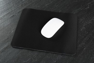 Photo of White wireless mouse and mousepad on black textured table