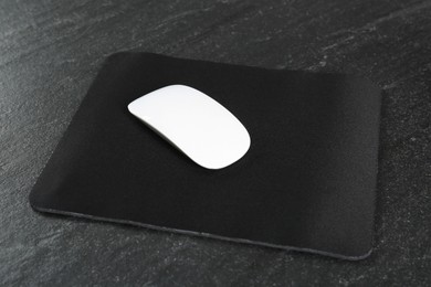 White wireless mouse and mousepad on black textured table