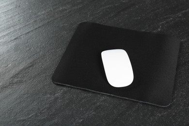 White wireless mouse and mousepad on black textured table