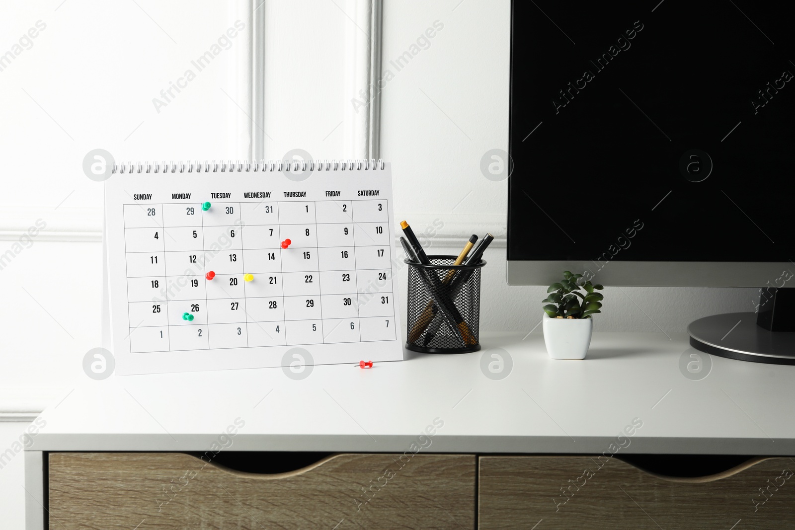 Photo of Timetable. Calendar with drawing pins and stationery on white table indoors