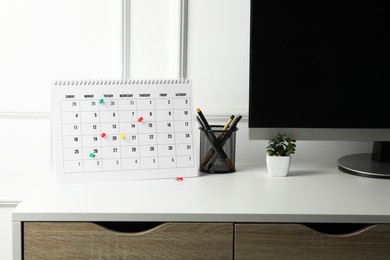 Photo of Timetable. Calendar with drawing pins and stationery on white table indoors