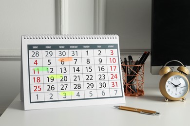 Timetable. Calendar with marked dates, alarm clock and stationery on white table indoors