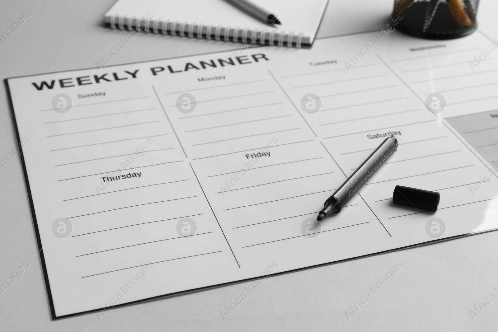 Photo of Timetable. Planner and black felt pen on grey table, closeup