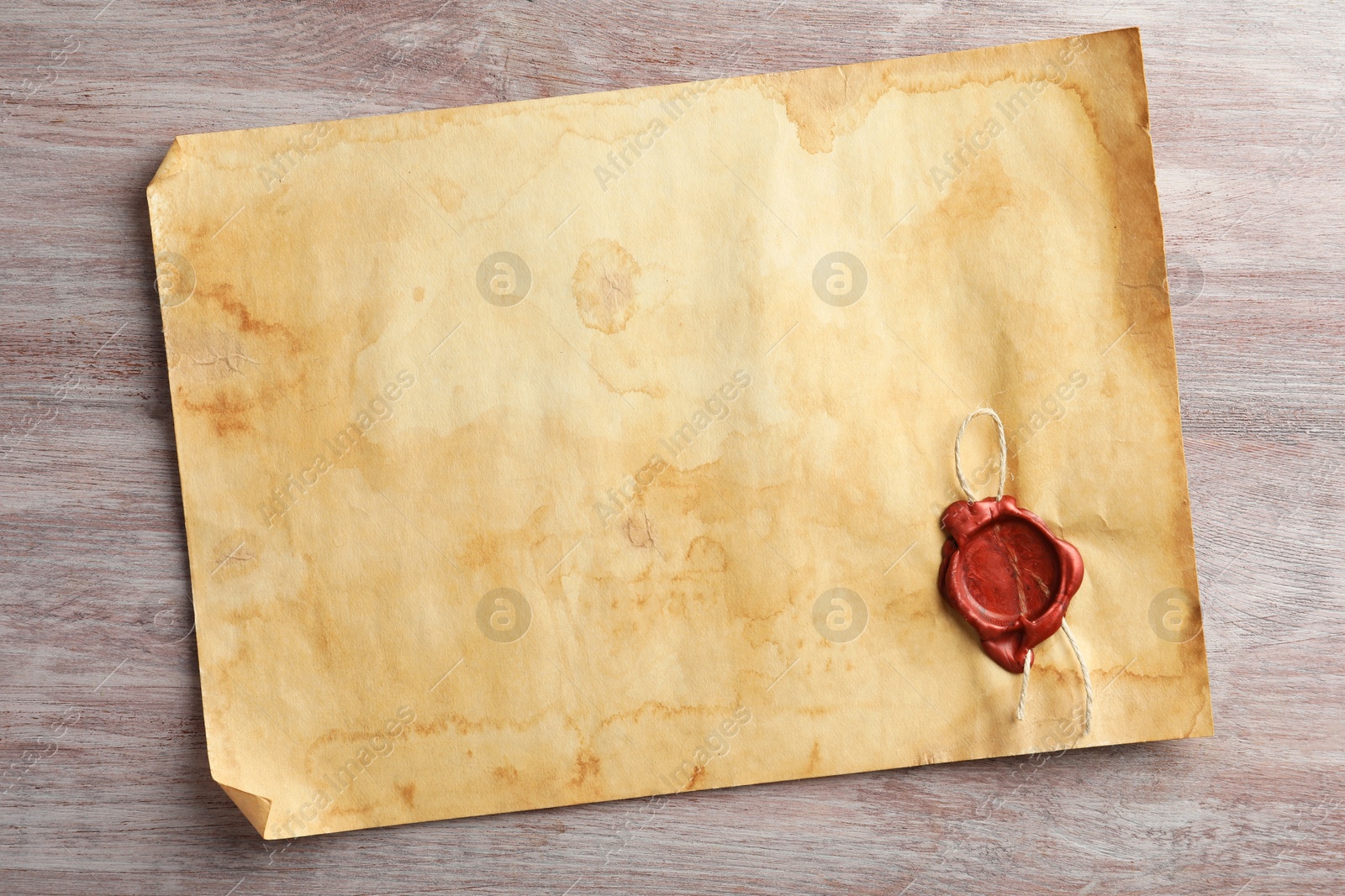 Photo of Sheet of old parchment paper with wax stamp on wooden table, top view