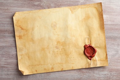 Photo of Sheet of old parchment paper with wax stamp on wooden table, top view