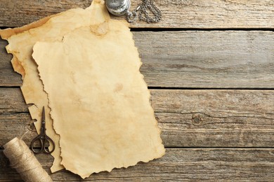 Photo of Sheet of old parchment paper, scissors, rope and pocket chain clock on wooden table, flat lay. Space for text