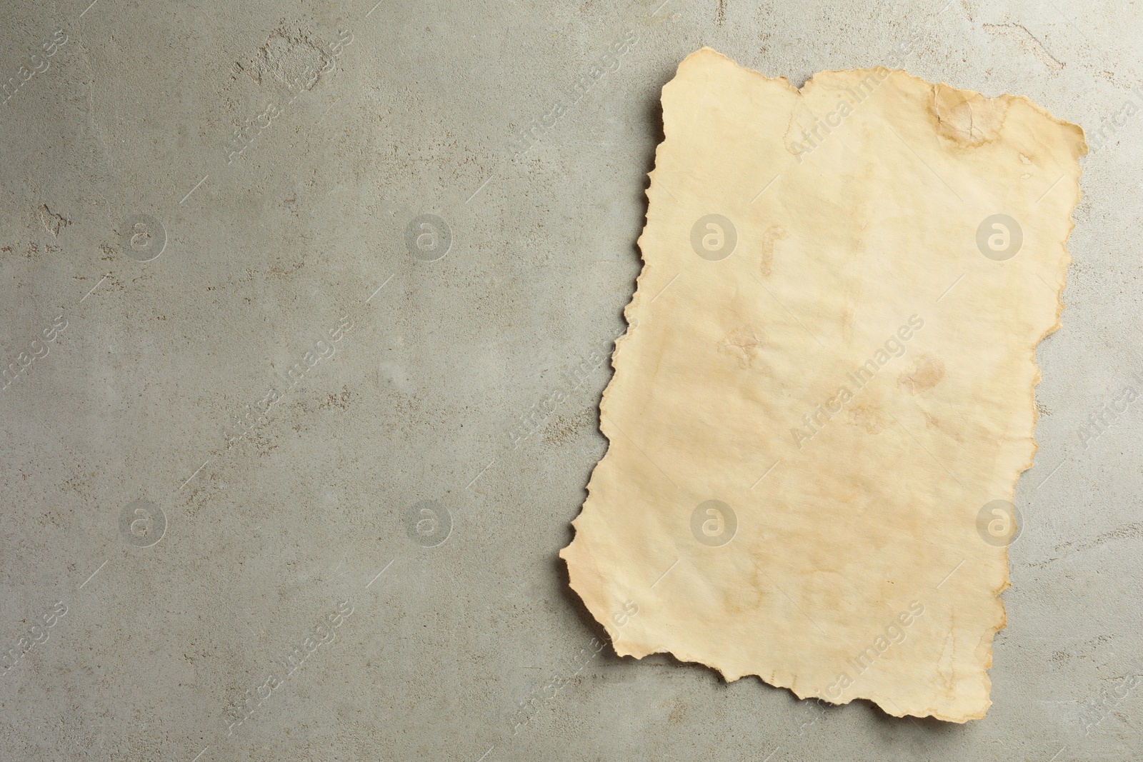 Photo of Sheet of old parchment paper on grey table, top view. Space for text