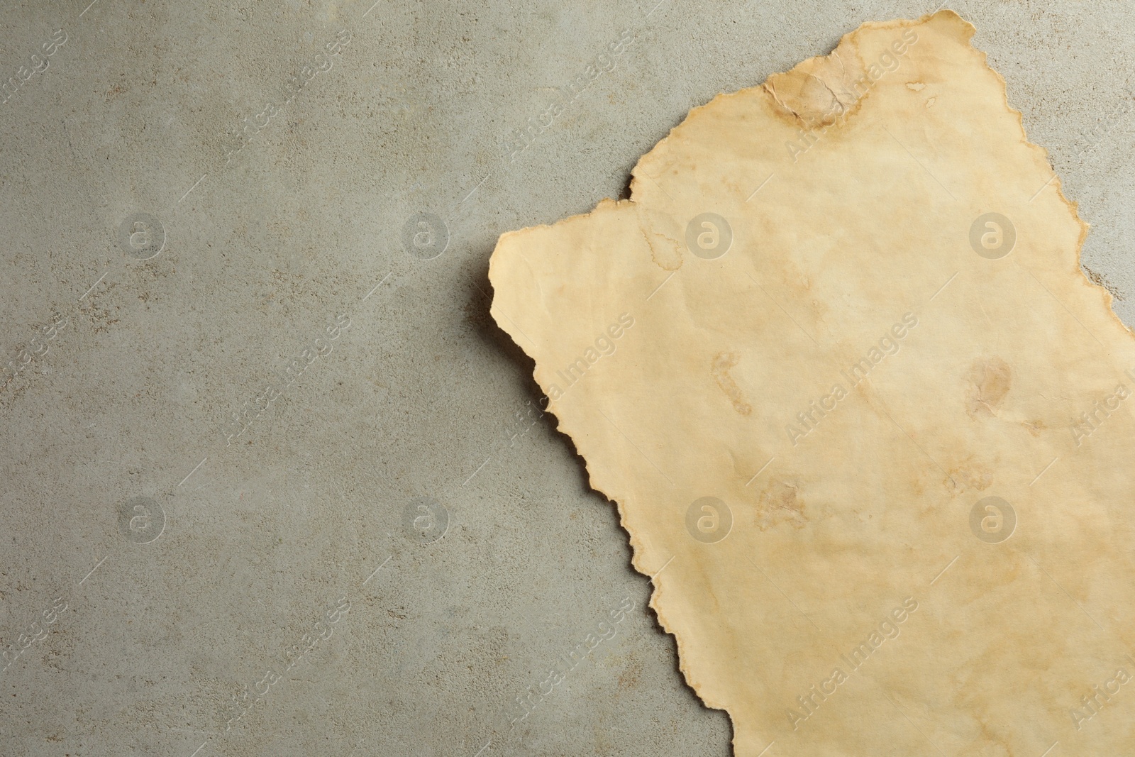 Photo of Sheet of old parchment paper on grey table, top view. Space for text