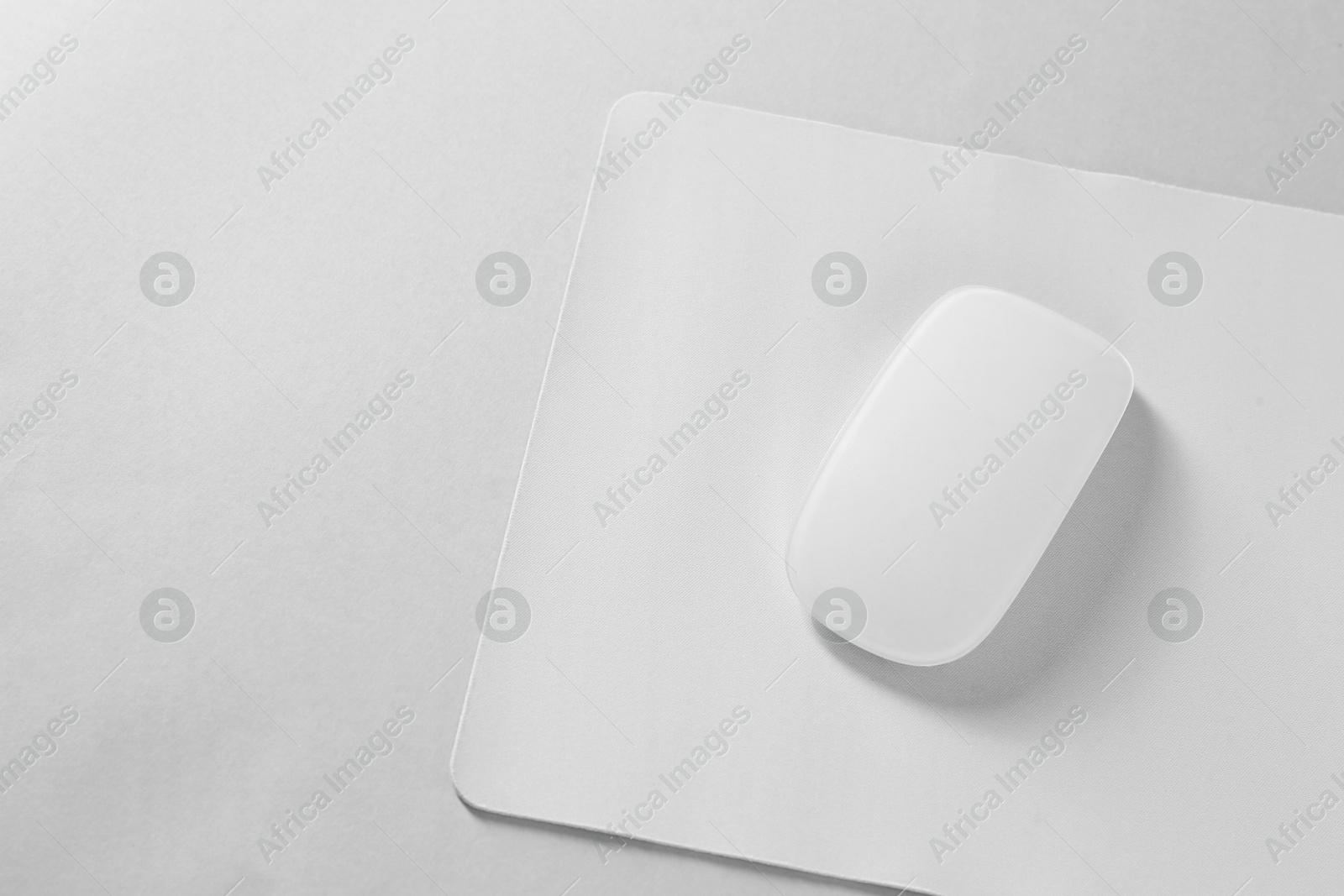 Photo of Wireless mouse and mousepad on white background, top view. Space for text