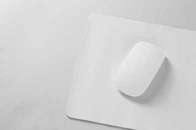 Wireless mouse and mousepad on white background, top view. Space for text